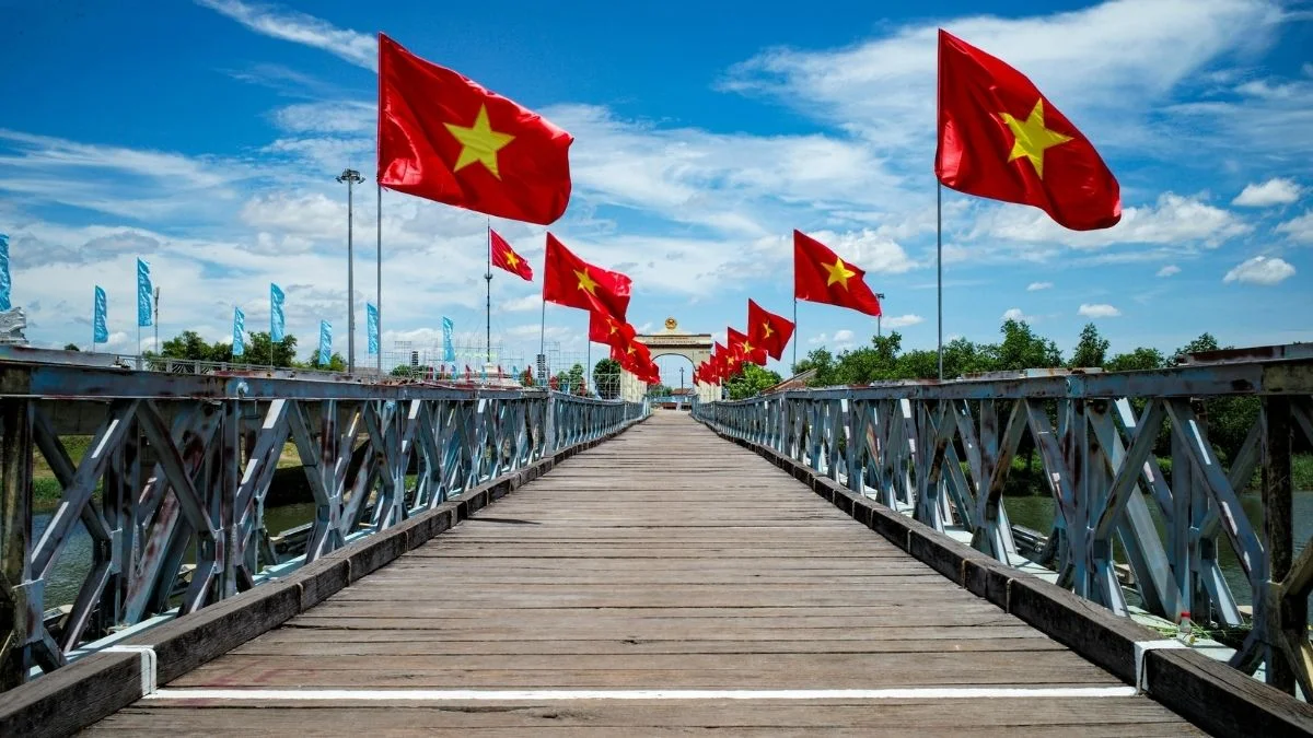 Nhiều lá cờ Việt Nam trên cây cầu gỗ bắc qua mặt nước